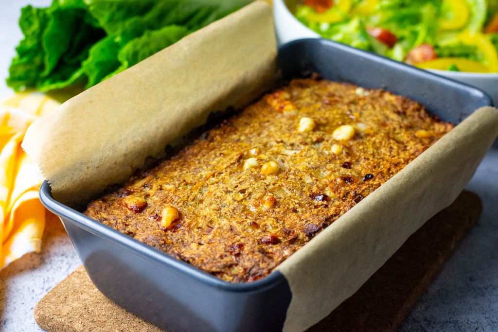 Cooked, golden brown cheesy turkey meatloaf still in the loaf pan.
