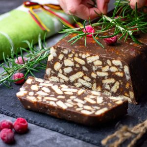 Lithuanian Lazy Cake, known as Tinginys, with one slice cut on a black board.