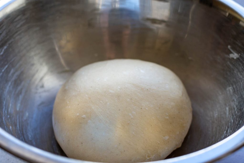 Ball of easter bread dough in a large metal bowl ready for proofing. 