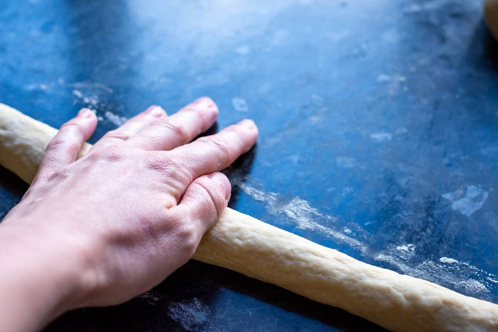 Rolling the dough into a long rope using palms of a hand.