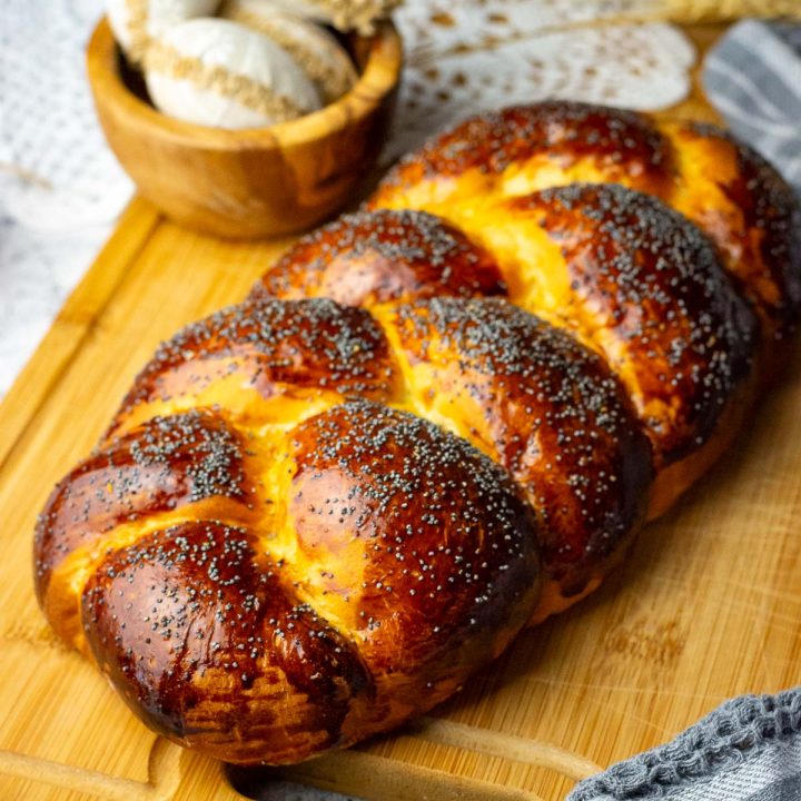 Dark Golden Brown Lithuanian Easter Bread (a.k.a. Mieline Pyne) on a large chopping board with a bread knife next to it.