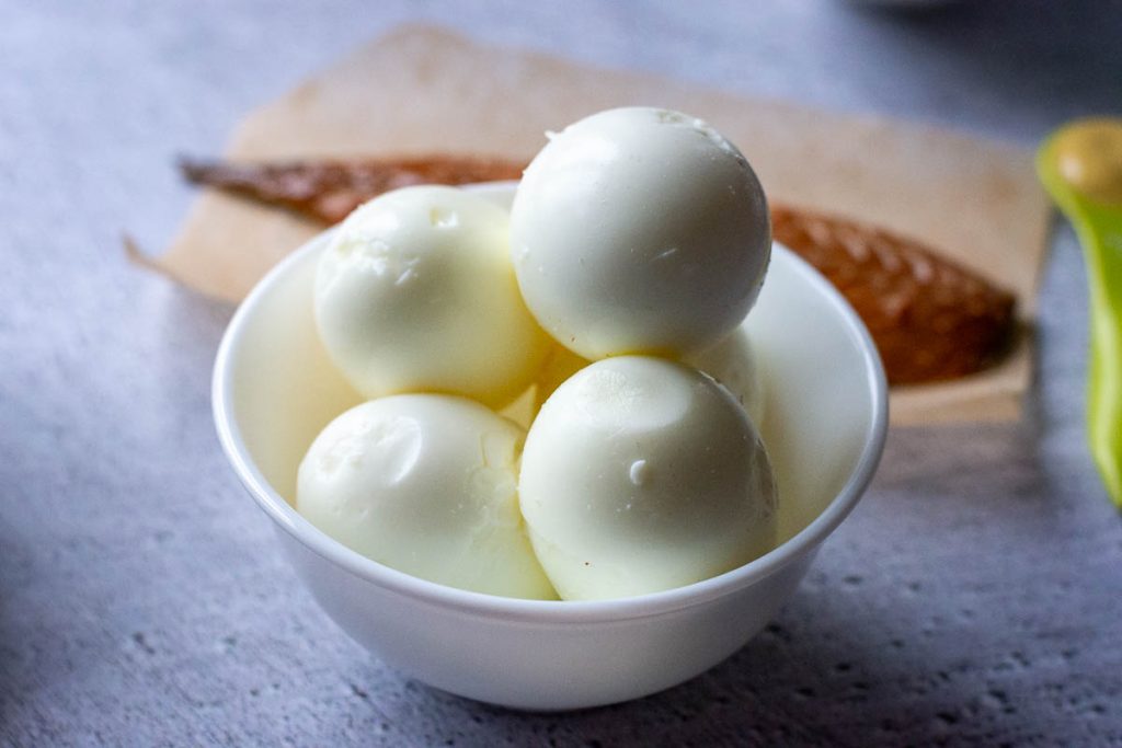 Peeled hard-boiled eggs in a small white bowl.
