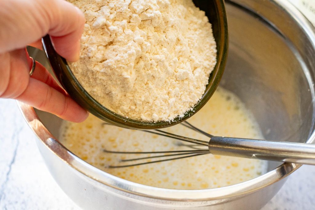 Adding flour to the milk and egg mixture.