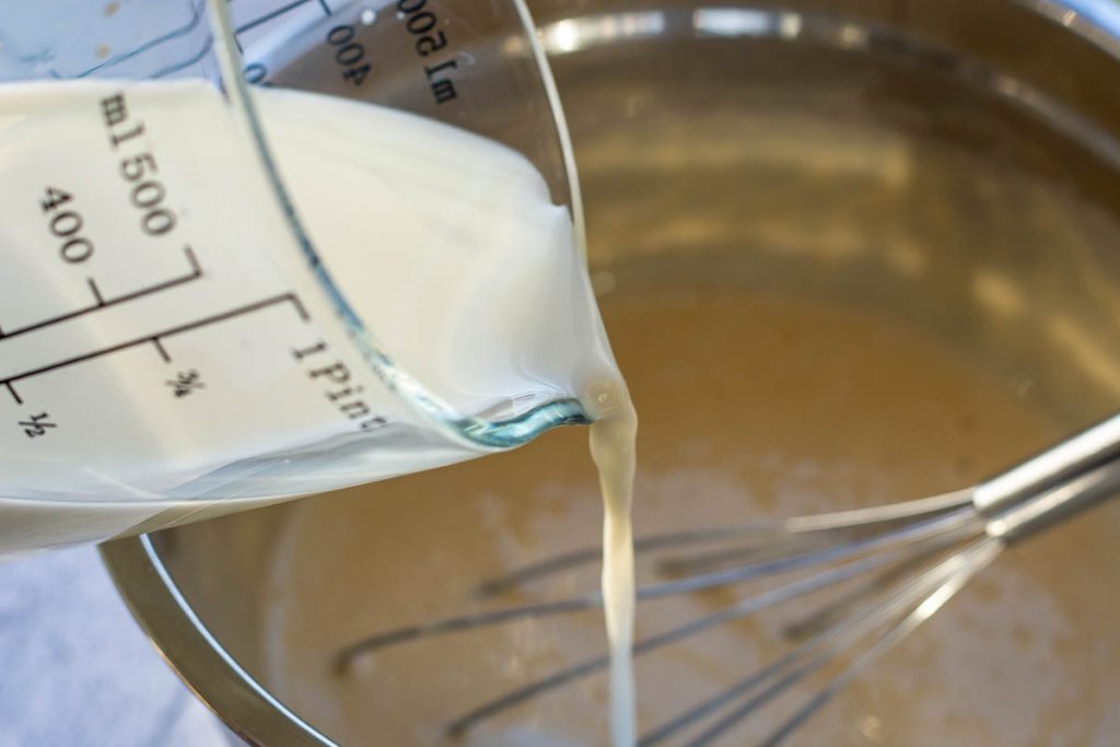 Pouring the milk from a jug to thin the crpee batter.