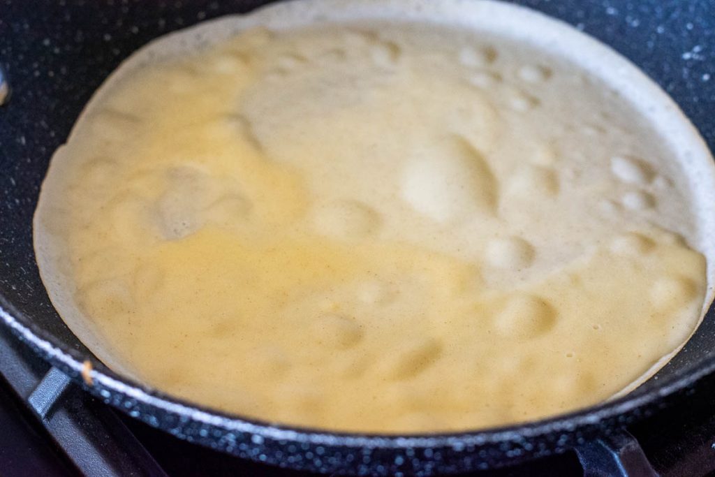 bubbled forming on the thin pancake frying in the pan.