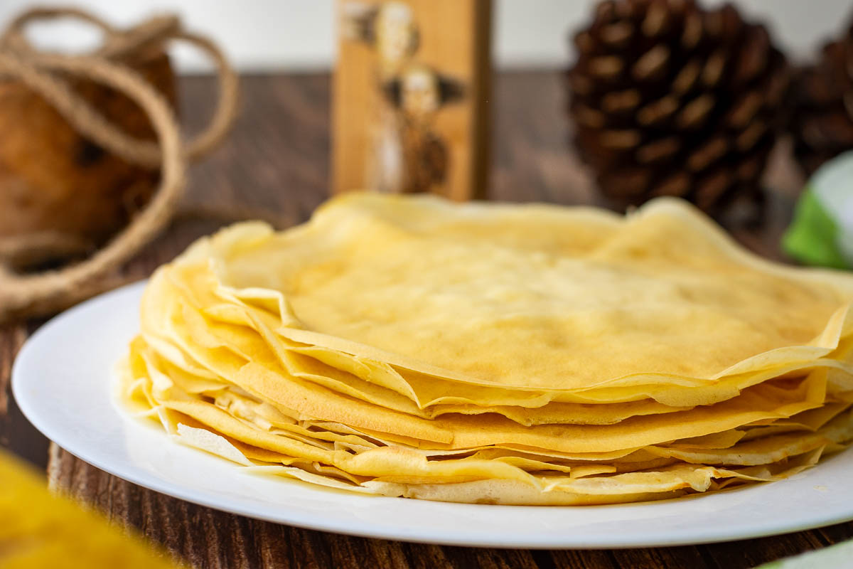 A stack of Lithuanian crepes, known as Lietiniai Blynai, on a white plate.