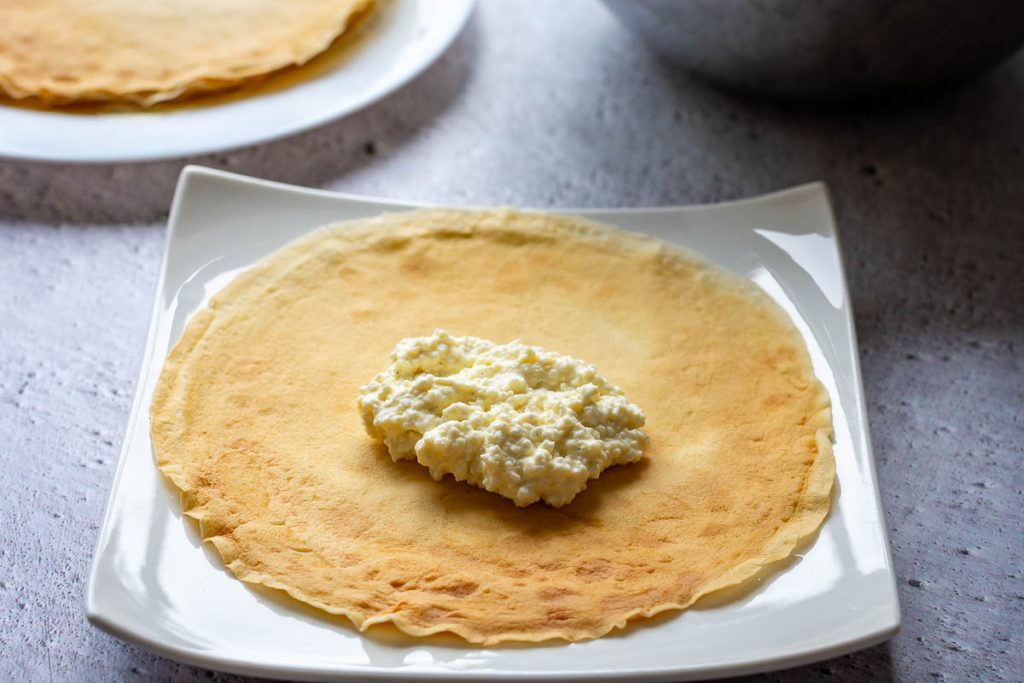 A spoonful of farmer's cheese filling in the centre of a crepe.