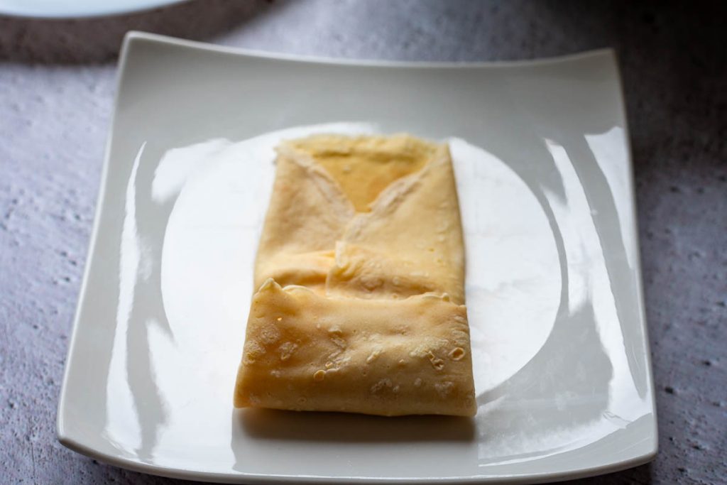 Folding the crepe to seal in the filling.