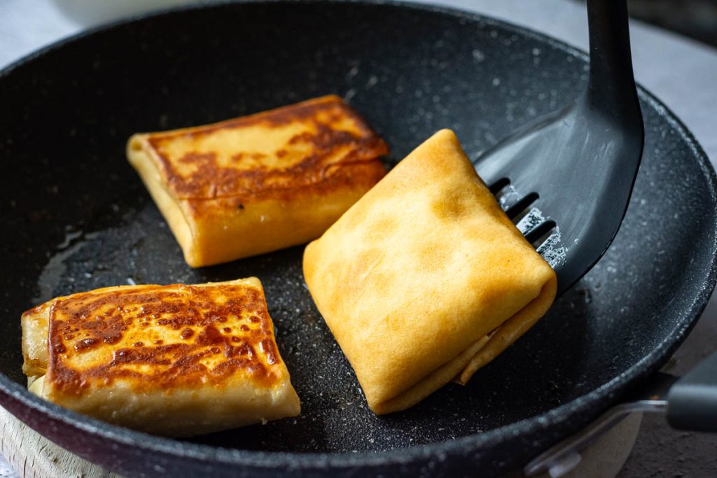 Flipping the crepes exposing golden brown cooked side.