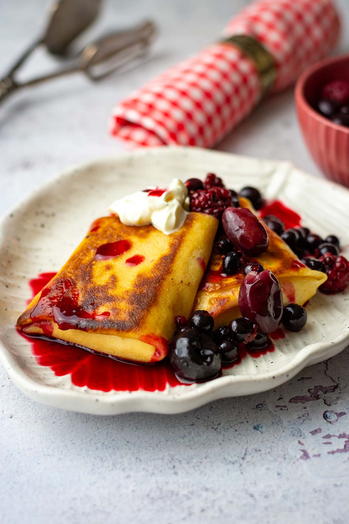 Two Lithuanian crepes with farmers cheese on a white plate.