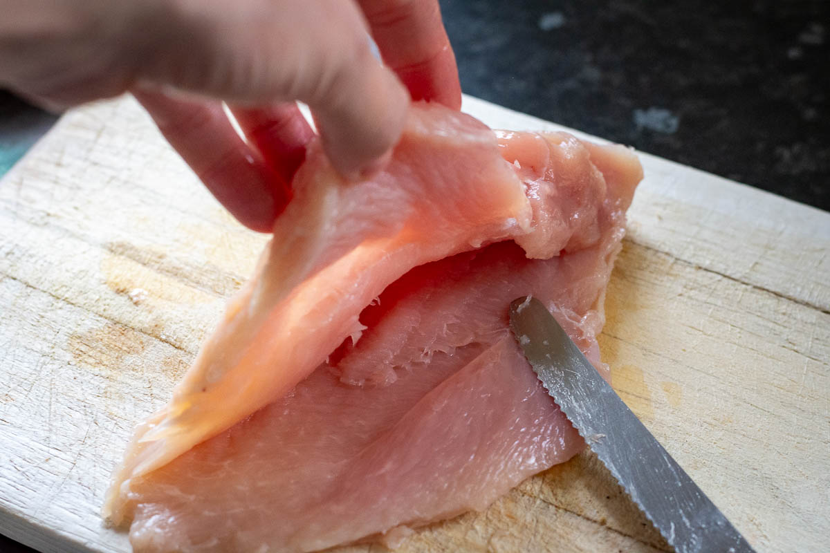Cutting chicken breast to butterfly it.