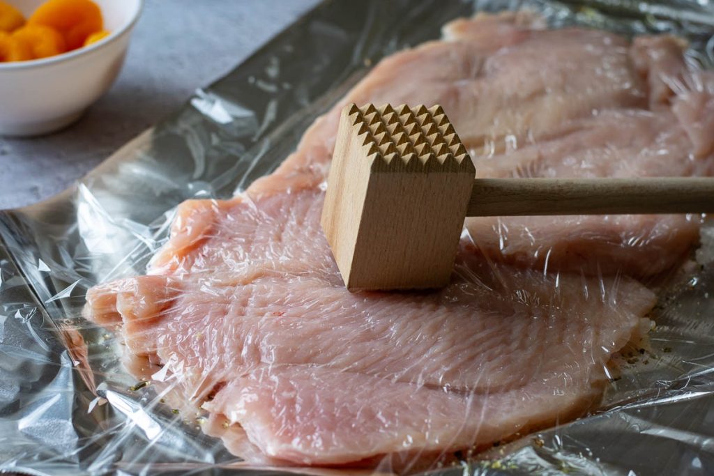 Bashing the chicken with meat tendetizer.