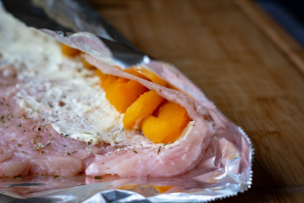 Rolling the filling into the chicken roulade.