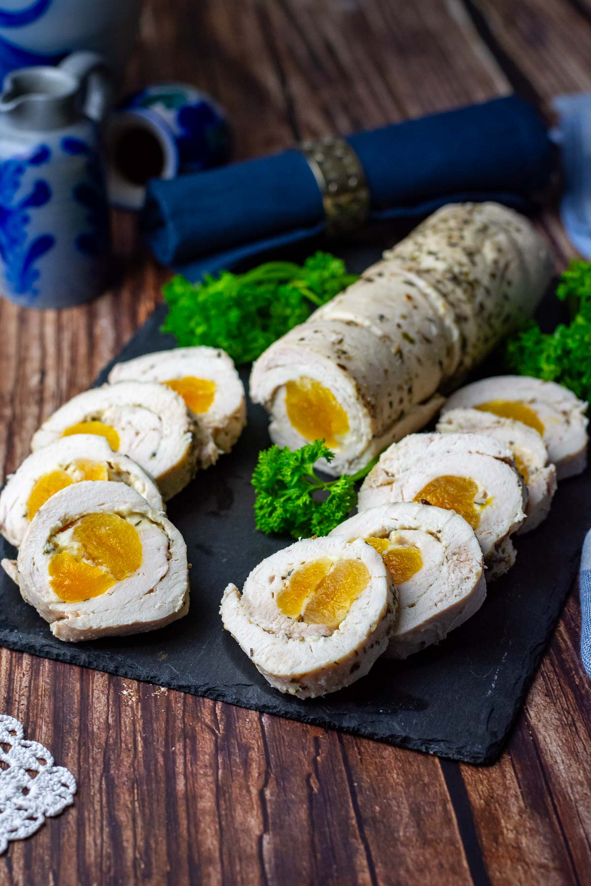 Lithuanian Chicken roulade with aprocot filling on a black slate board garnished with parsley.