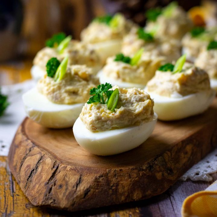 Mackerel stuffed eggs on a wooden board garnished with parsley.