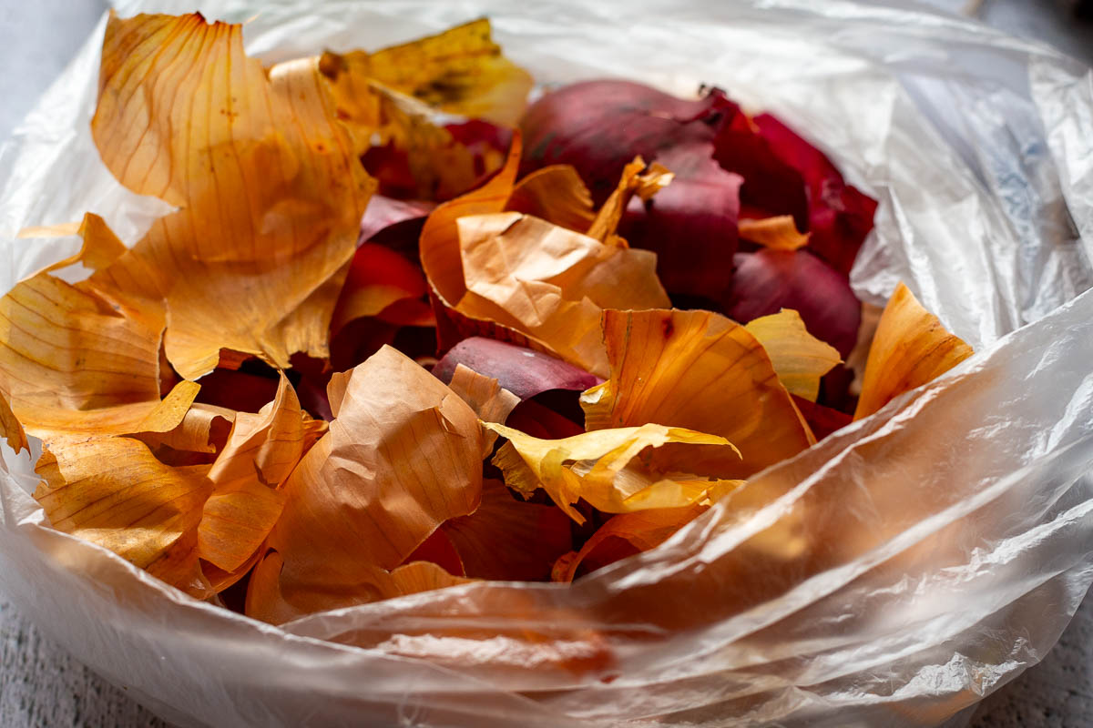 A plastic bag full of red and brown onion skins. 