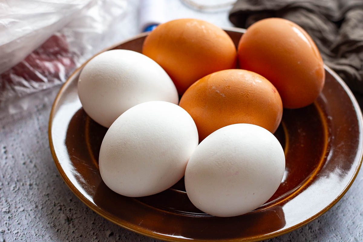 Brown and white shelled eggs on a brown plate. 