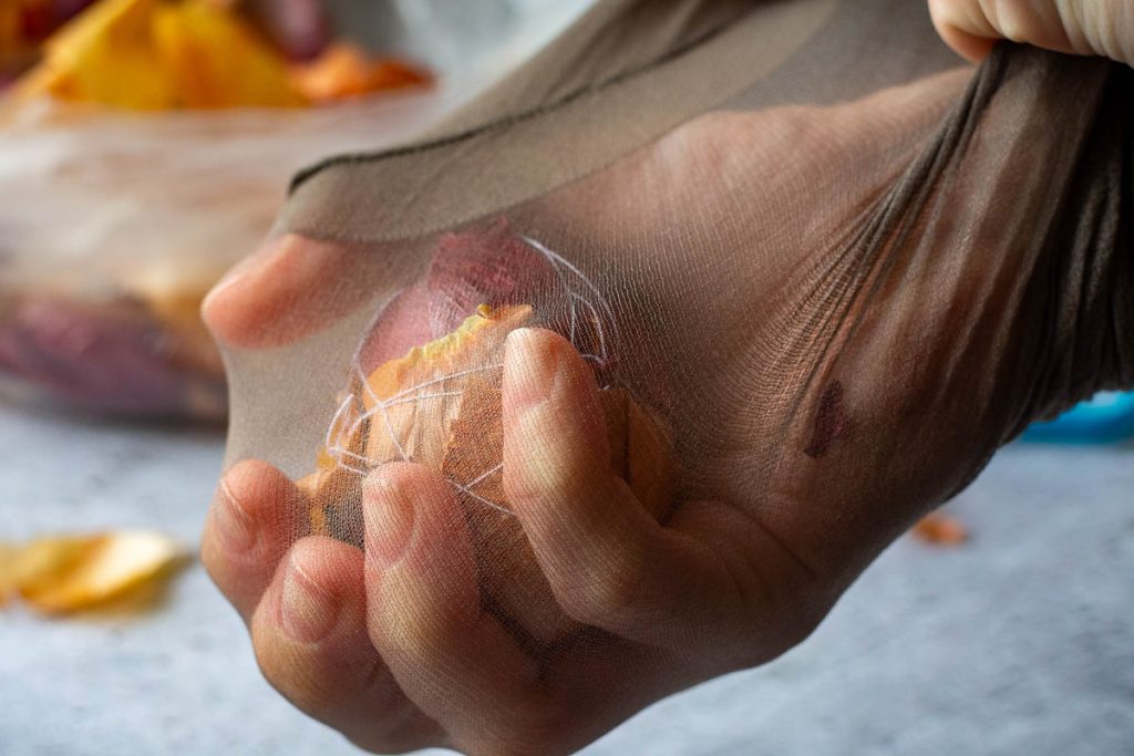 Placing onion skin egg in a nylon stocking. 