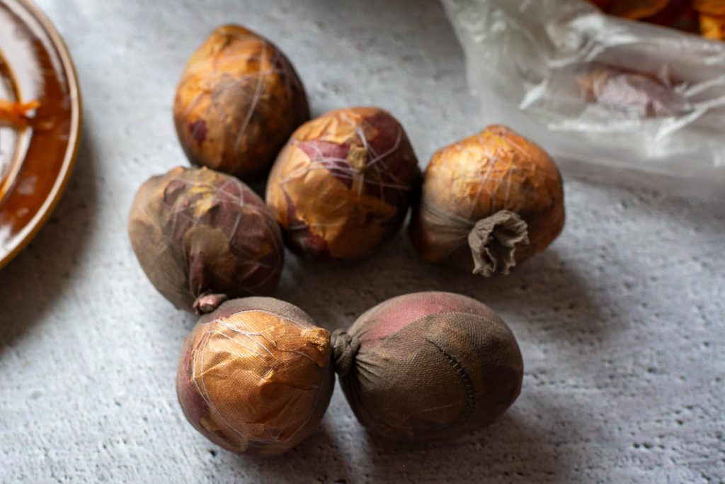 Six onion skin wrapped eggs in a nylon stocking with nots tied in between them. 