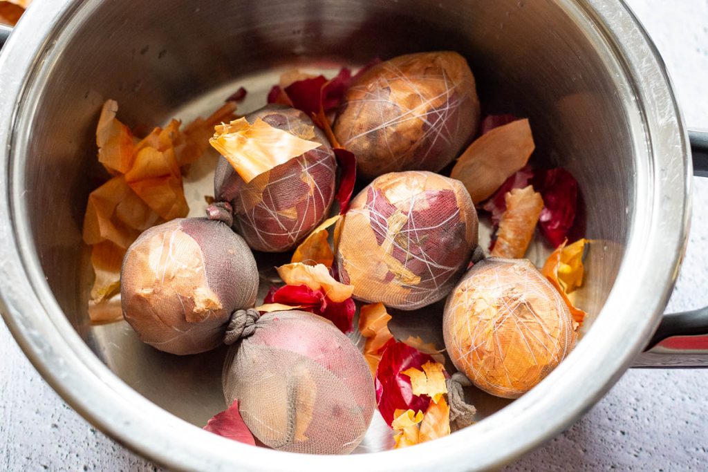 Lithuanian Easter eggs in nylon stocking in a pot with extra onion skins on top. 