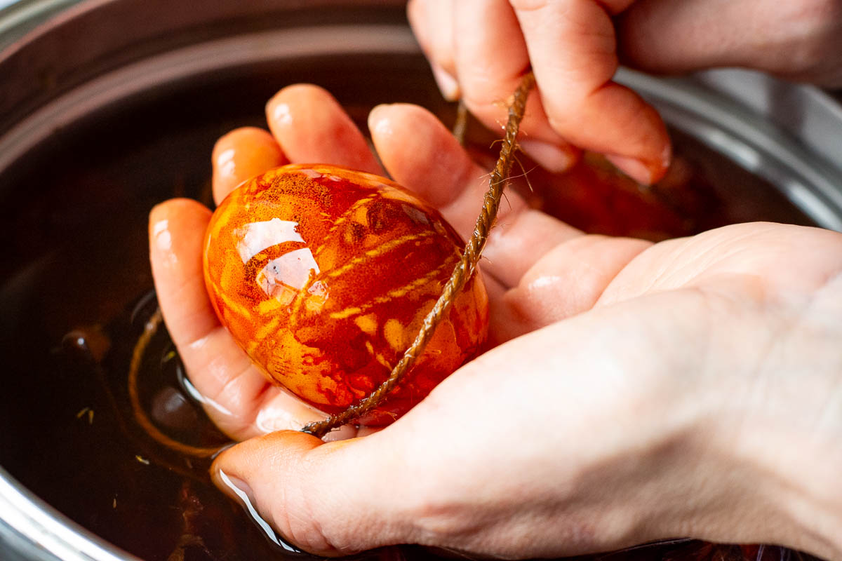 Onion skin dyed egg with kitchen twine wrapped around it. 