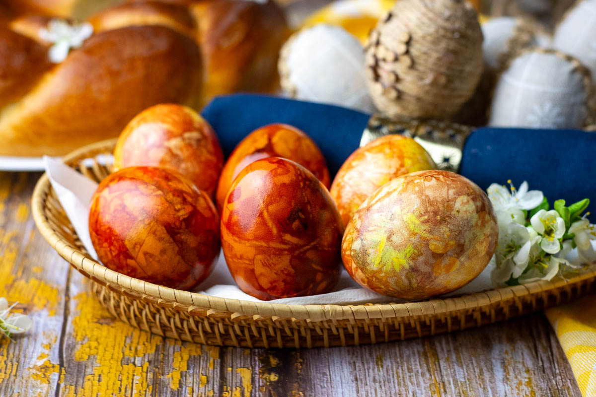Six Lithuanian Easter eggs dyed with onion skins on a wicker platter.