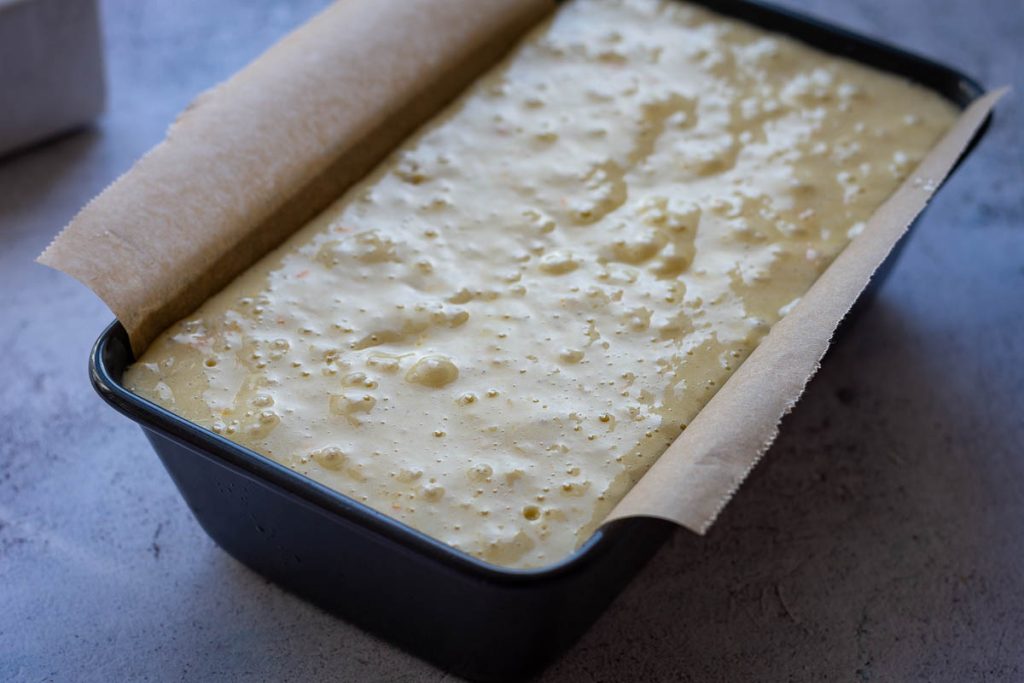 Orange cake batter poured into the loaf pan. 