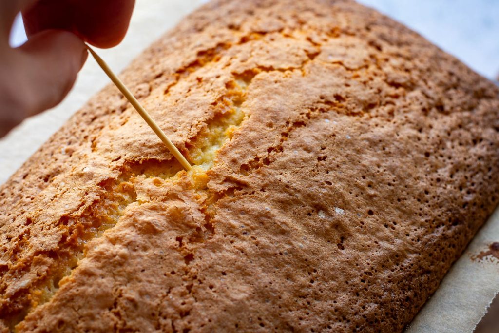 Checking if orange loaf cake is cooked by insterting a wooden skewer into the centre of the cake. 