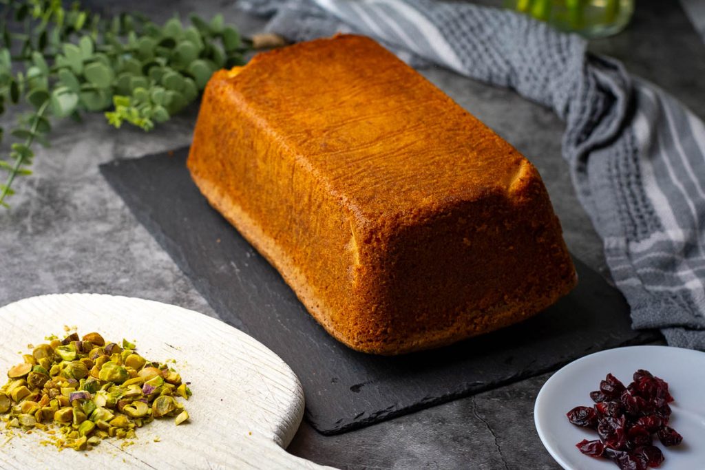 Lithuanian orange cake turned out of the tin onto a black slate board. 