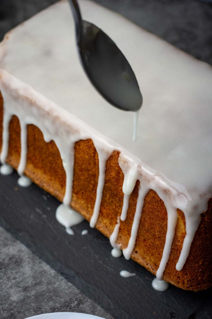 Spooning orange glaze over the cake, letting it drip down the sides. 