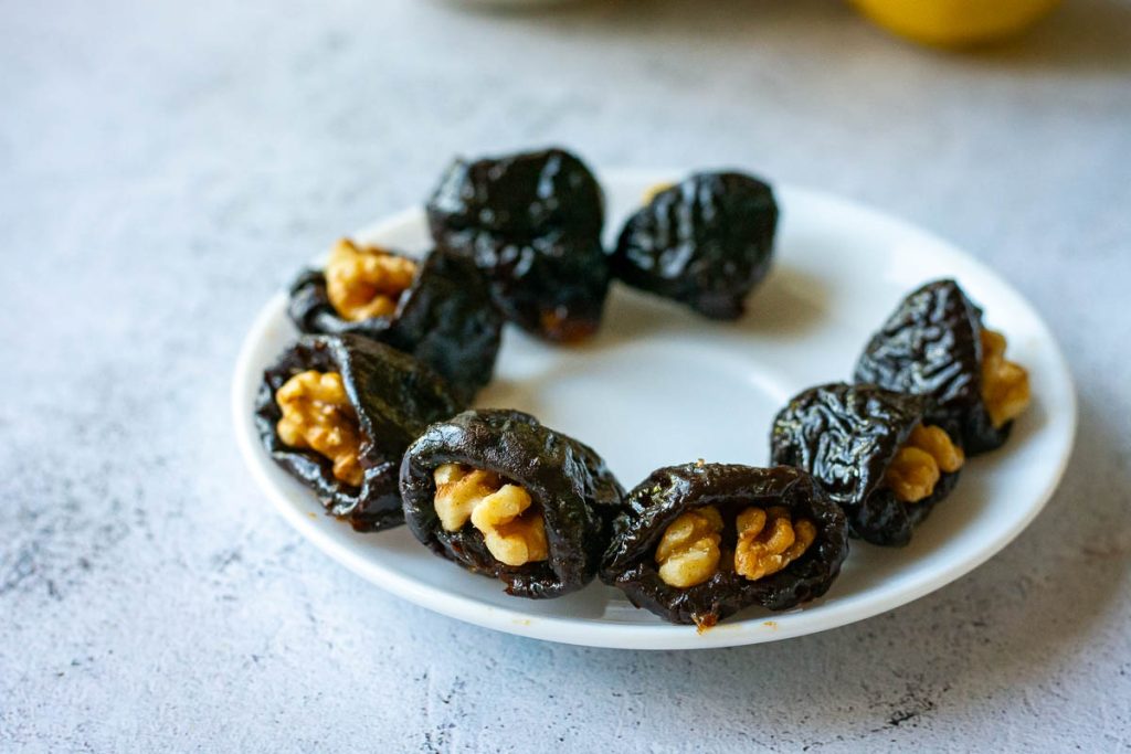 8 walnut stuffed prunes on a small white saucer. 