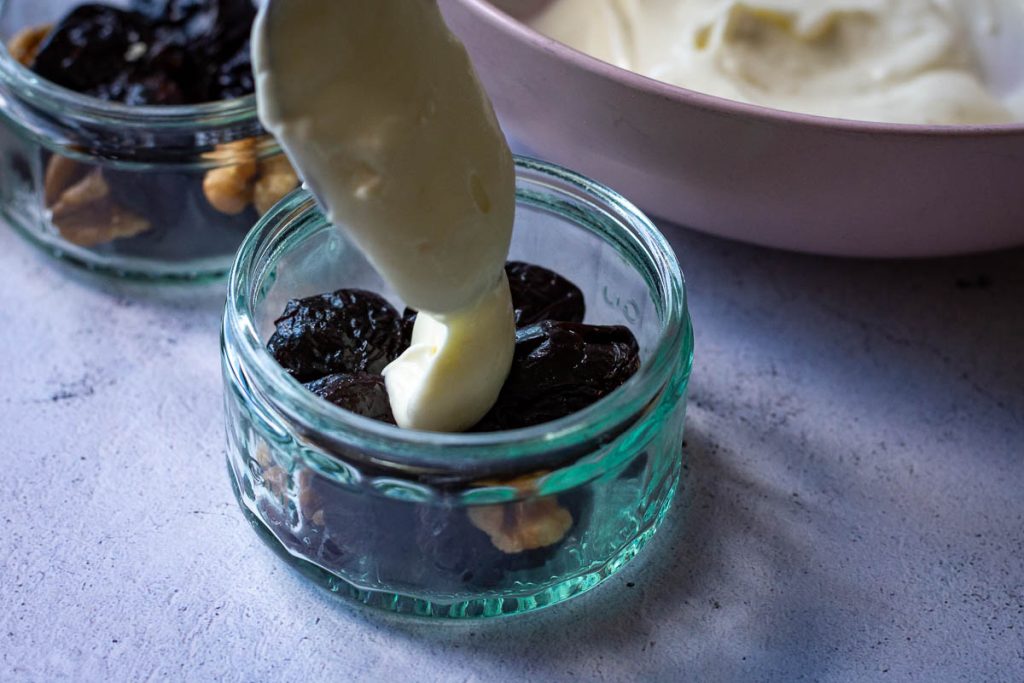 Topping walnut stuffed prunes with lemon creme fraiche. 