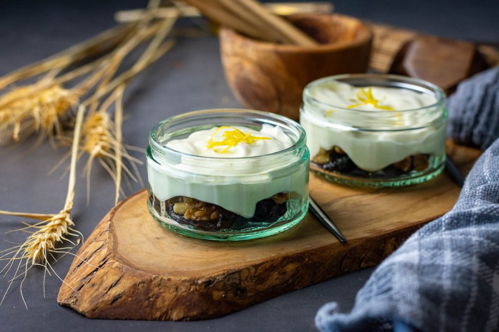 Assembled walnut and prune dessert in two pots on a decorative wooden board. 
