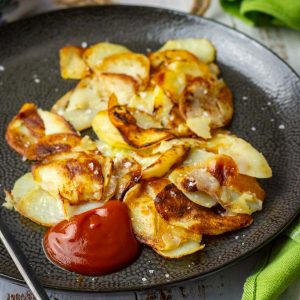 Lithuanian Pan Fried Sliced Potatoes With Ketchup in a black plate.