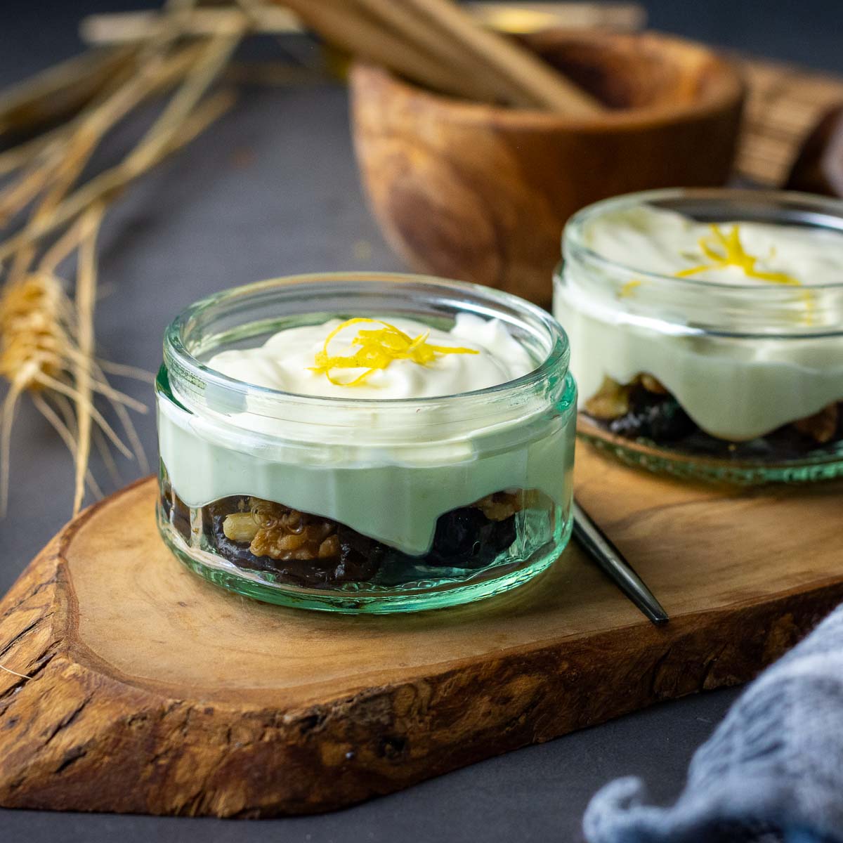 Two small pots with walnut stuffed prunes and lemon cream on top.