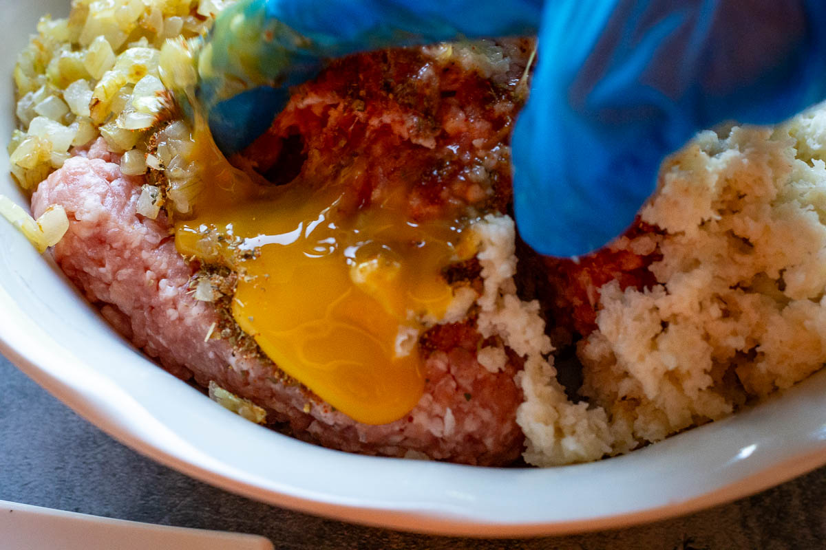 Mixing the meat mixture with a gloved hand.