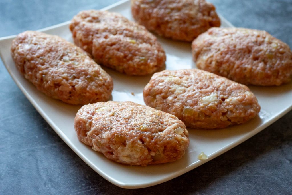 Shaped Lithuanian pork patties on a white plate.