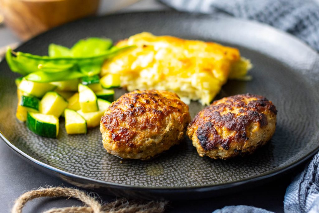Two meatballs served on a large black plate.