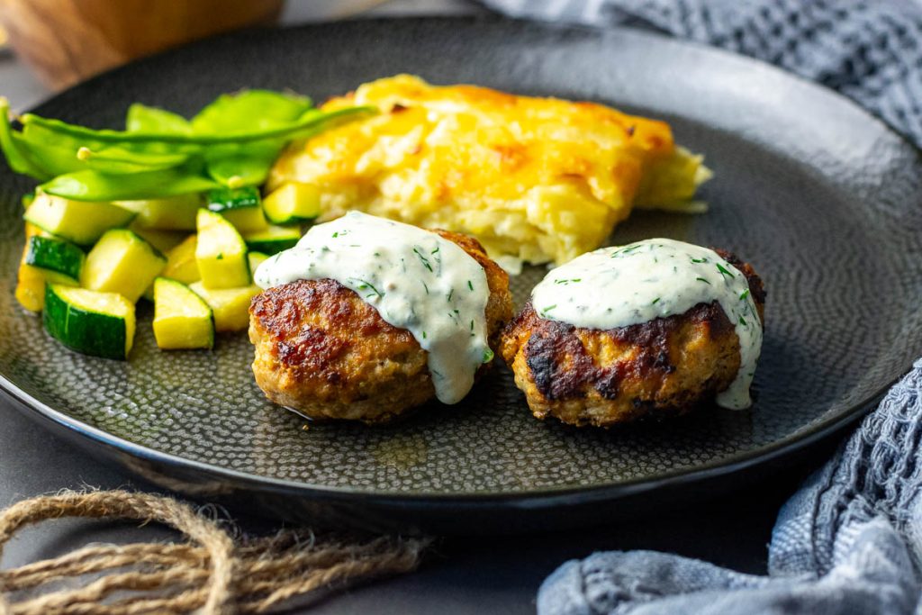 Lithuanian meatballs with sour cream sauce on top.