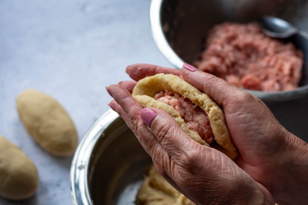 Encasing the meat filling into the potato dough.