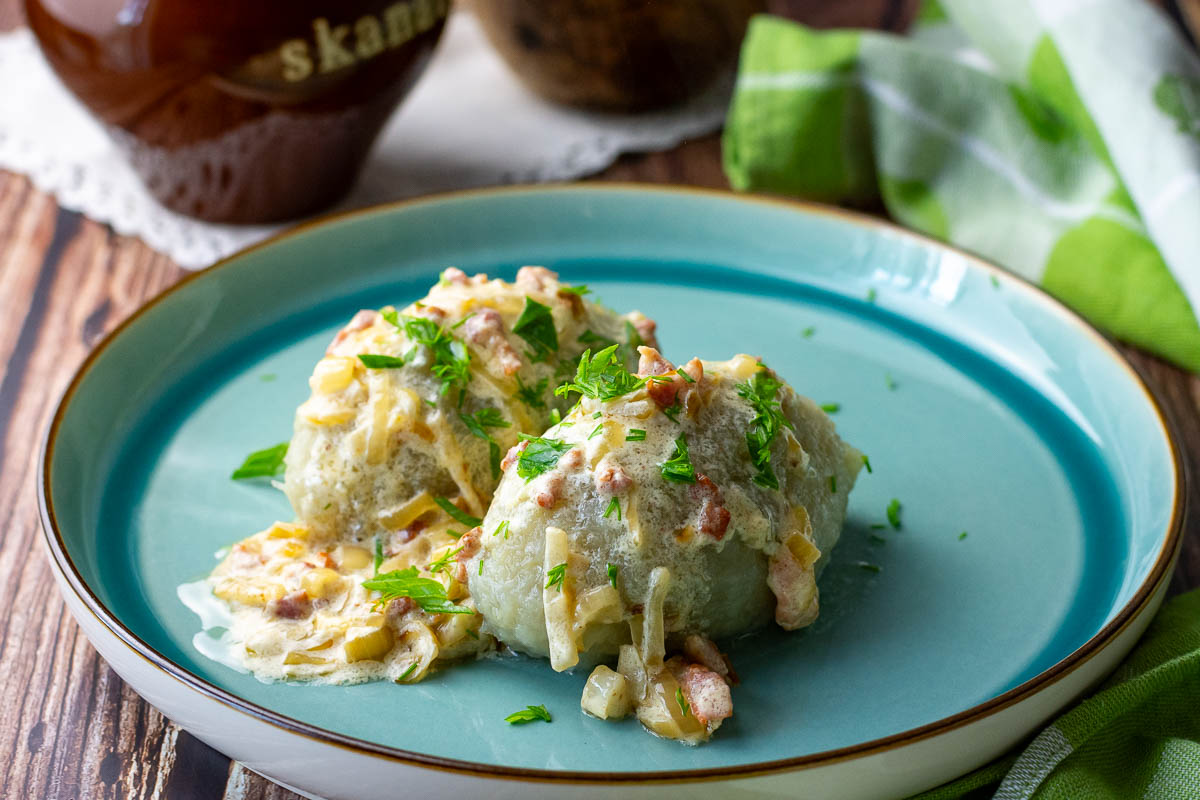 Lithuanian zeppelins topped with sour cream, bacon and onion sauce.