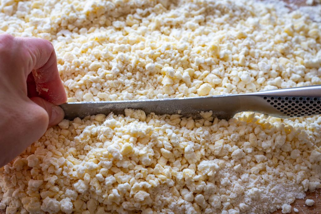 Chopping the flour, butter and farmer's cheese cookie dough with a large knife.