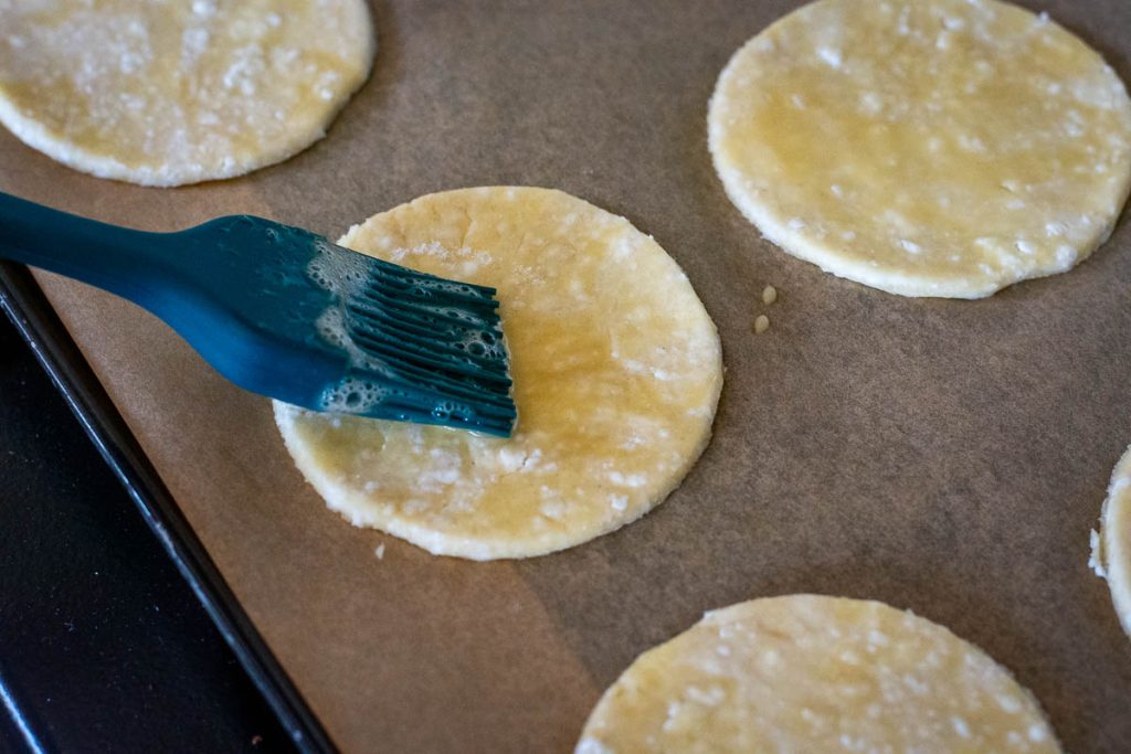 Brushing the cookie dough disks with egg.