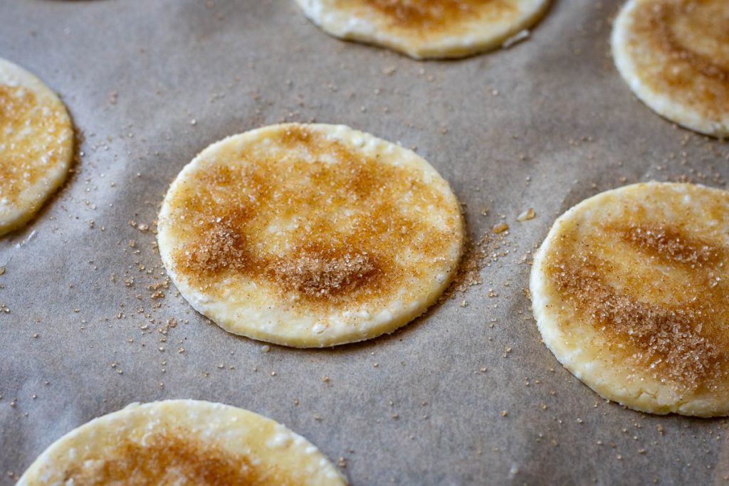 Cinnamon sugar sprinled over the egg washed dough discs.