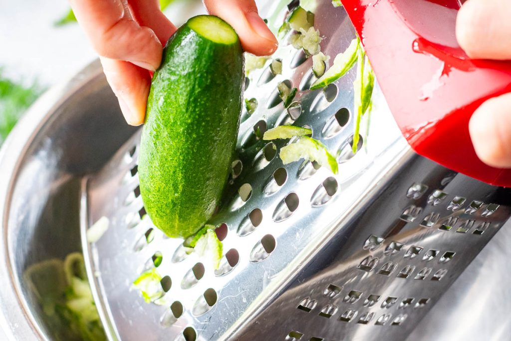 Coarsely grating cucumber.