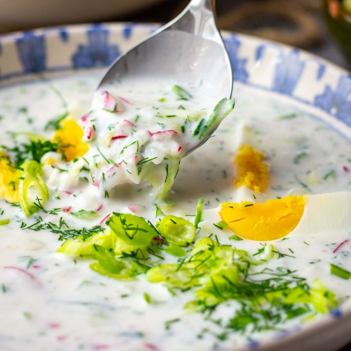 A spoonful of Lithuanian Kefir soup being lifted out of a bowl.
