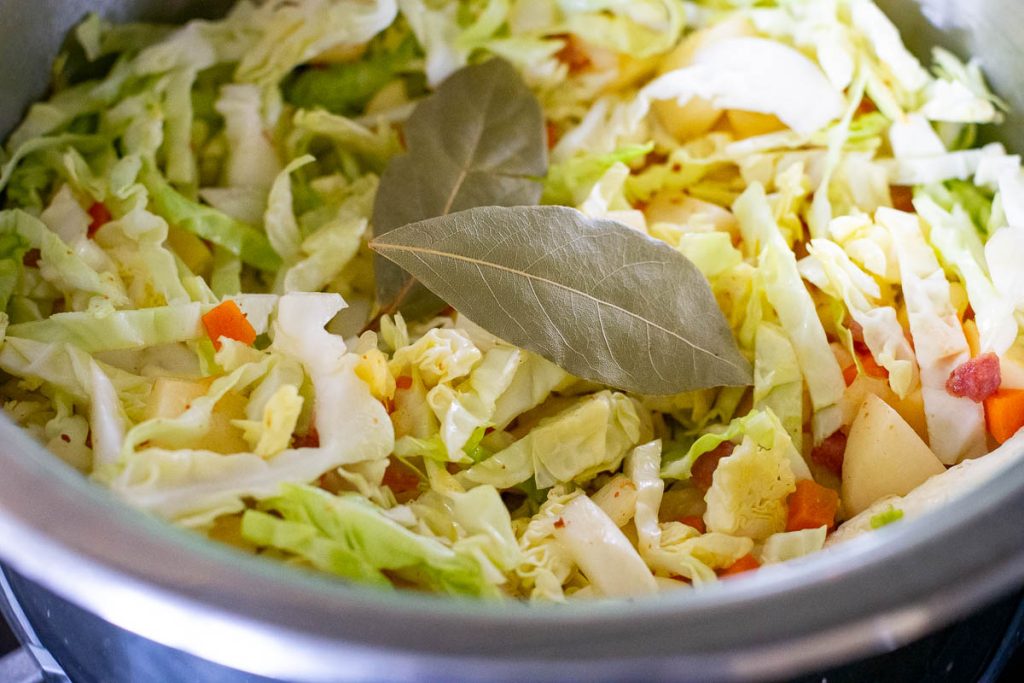 Cabbage and bay leaves added to the soup pot.