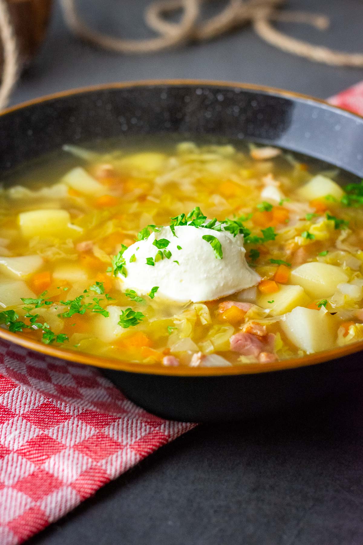 Lithuanian Cabbage soup with bacon served with a dollop of sour cream.