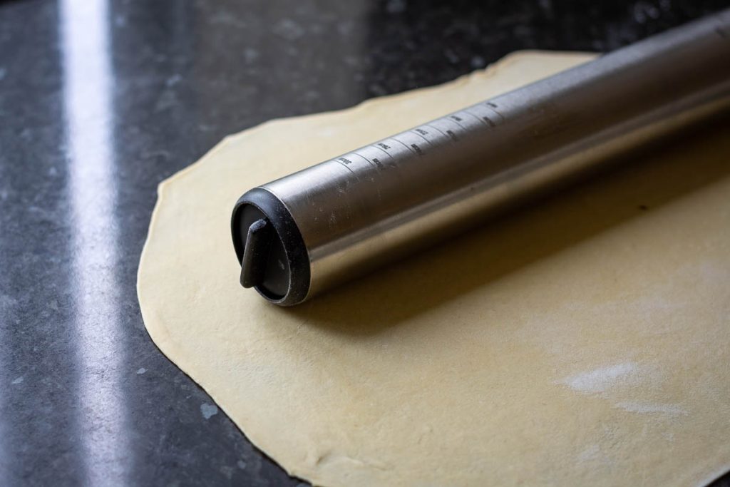Dough being rolled into a thin rectangle.
