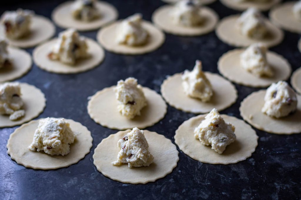 A tesp of sweet curd cheese filling on each of the dough circle.